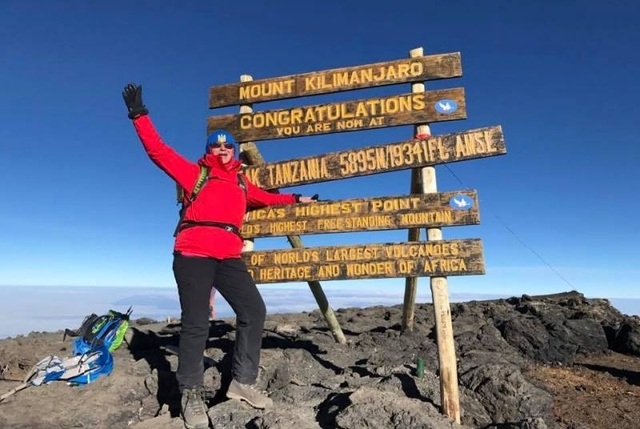 Напис на дошках: "Гора Кіліманджаро. Вітаємо! Ви тепер знаходитеся у найвищій точці Африки і на найвищій - окремо стоячій горі та на найбільшому вулкані в світі." (деякі слова нерозбірливо)