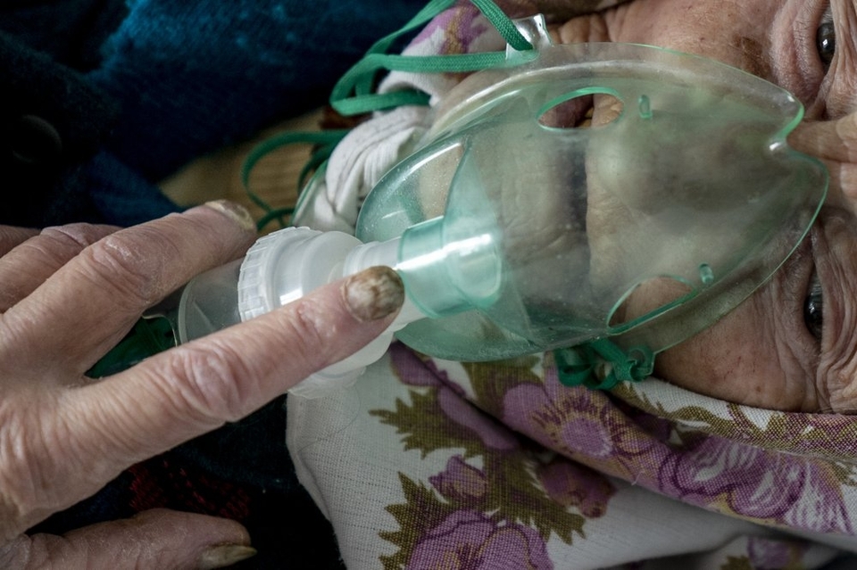 На цій фотографії, зробленій у п’ятницю, 1 травня 2020 року, літня жінка, пацієнтка з коронавірусом, дихає за допомогою кисневої маски всередині лікарні в Почаєві, Україна. (АП Фото / Євген Малолетка)
