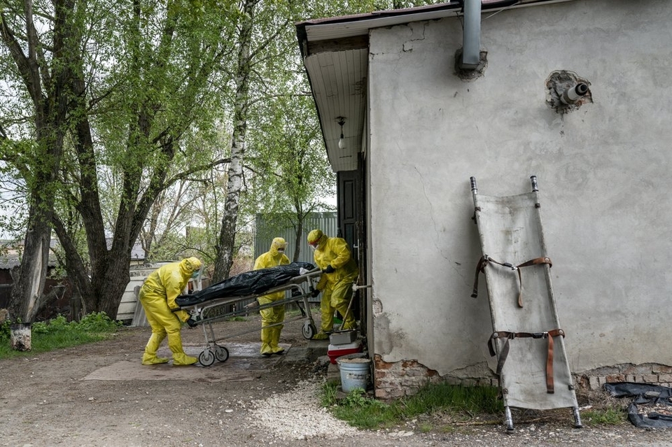 На цій фотографії, зробленій у четвер, 30 квітня 2020 року, двері моргу у Тернополі, Україна, патологоанатоми, які одягають спеціальні костюми для захисту від коронавірусу, транспортують тіло людини, яка померла від коронавірусу. (АП Фото / Євген Малолетк