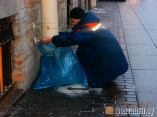 Санкт-Петербурзький комунальник кріпить пакет на водостічну трубу