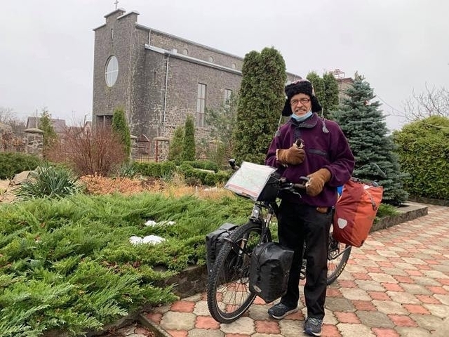 Лео -- в рукавицях і на велосипеді -- біля костелу в Сарнах