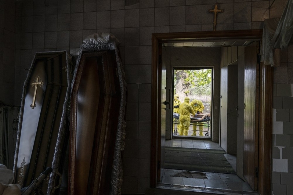 На цій фотографії, зробленій у четвер, 30 квітня 2020 року, патологоанатоми, одягнені в спеціальні костюми для захисту від коронавірусу, розтинають тіло чоловіка, який помер від коронавірусу, поза моргом лікарні в Тернополі, Україна. (АП Фото / Євген Мало