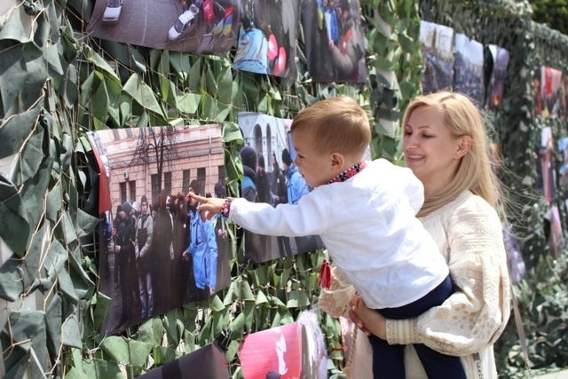 Наталія Муляренко з сином Олексієм розглядають фото на виставці до Дня Конституції України. Фото — тут і далі — Радіо Трек.