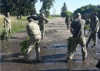 Солдати вимітають віниками багнюку з калюж. Фото "24 канал".