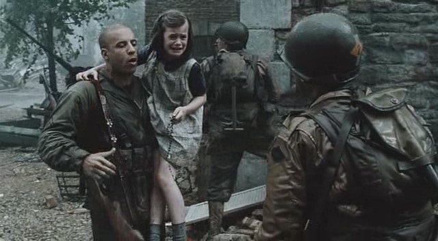 Бравий американський вояка у виконанні Віна Дизеля тримає врятовану з-під куль дівчинку. Кадр з фільму "Врятувати рядового Раяна".